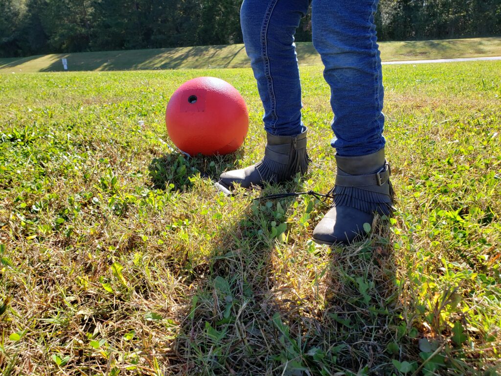 Image of a ball and player on a grass field.